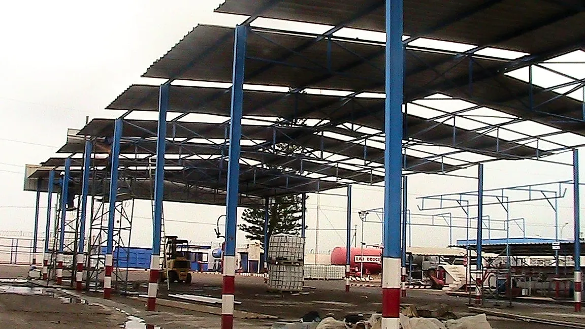 Charpente métallique d'un grand auvent industriel montée par CIMTI, poteaux bleus et toiture en bac acier